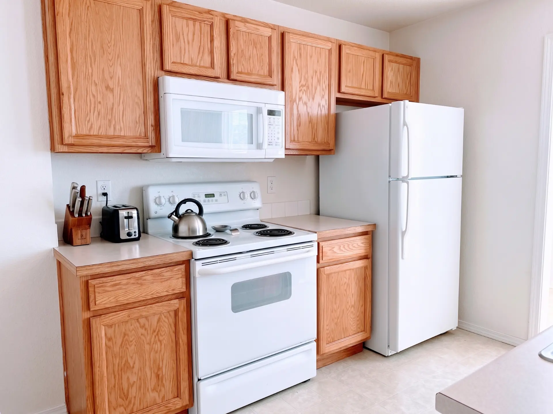 Private rental kitchen with oak cabinets, electric range, microwave, and full-size refrigerator
